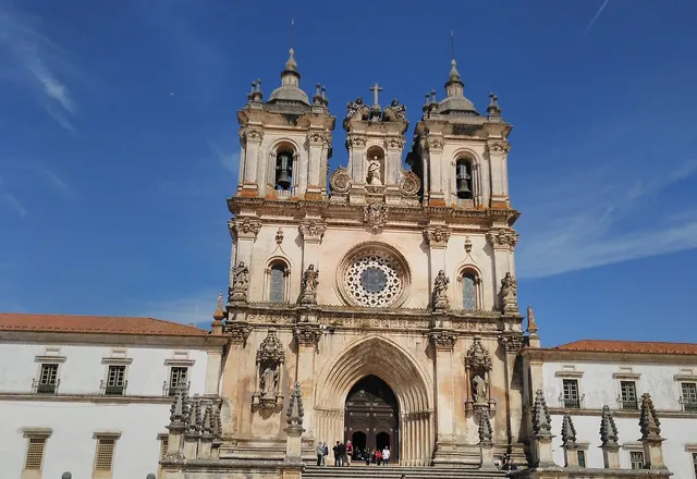 Fachada gótica do Mosteiro de Alcobaça sob céu azul