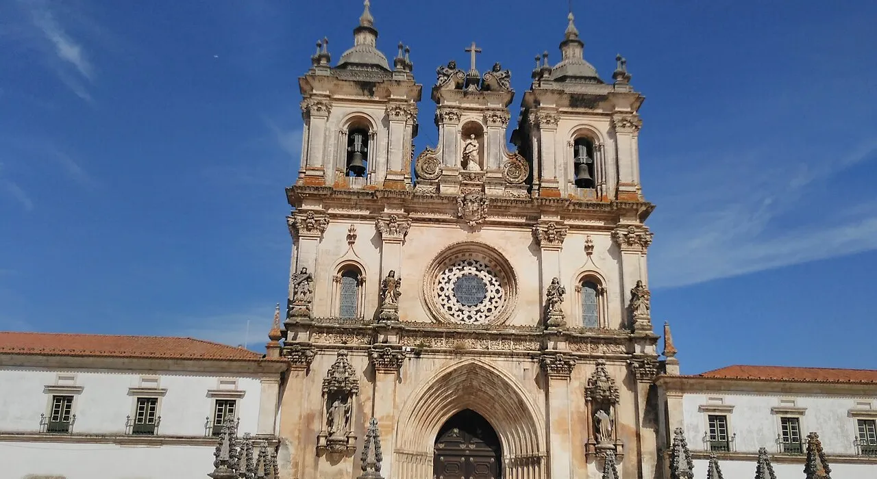 Fachada gótica do Mosteiro de Alcobaça sob céu azul